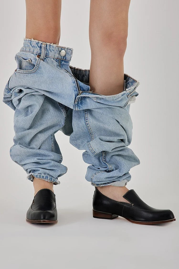 Black leather slip-on loafers worn with slouchy light-wash denim jeans