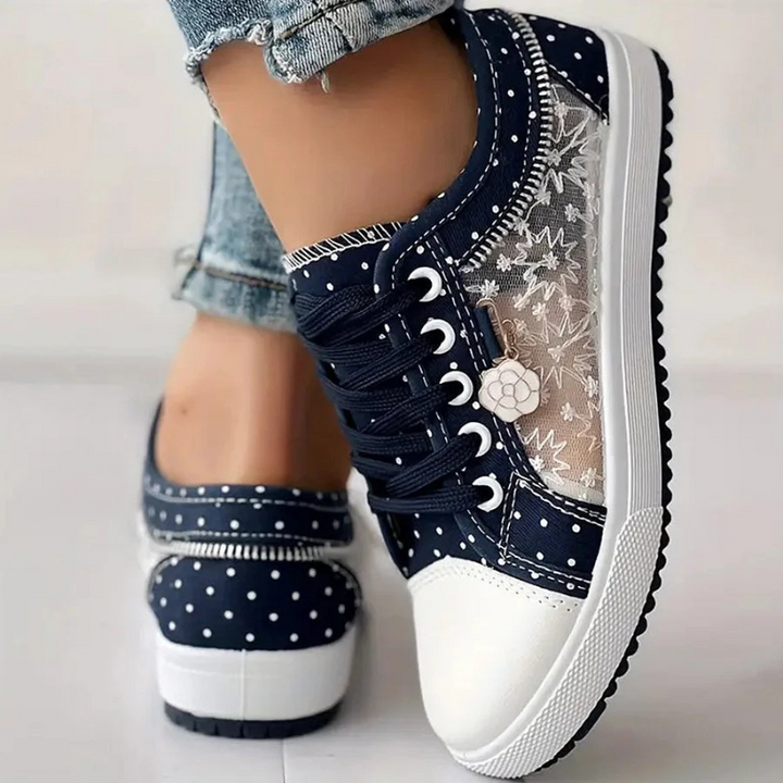 Navy blue polka dot sneakers with lace cutout design and flower charm