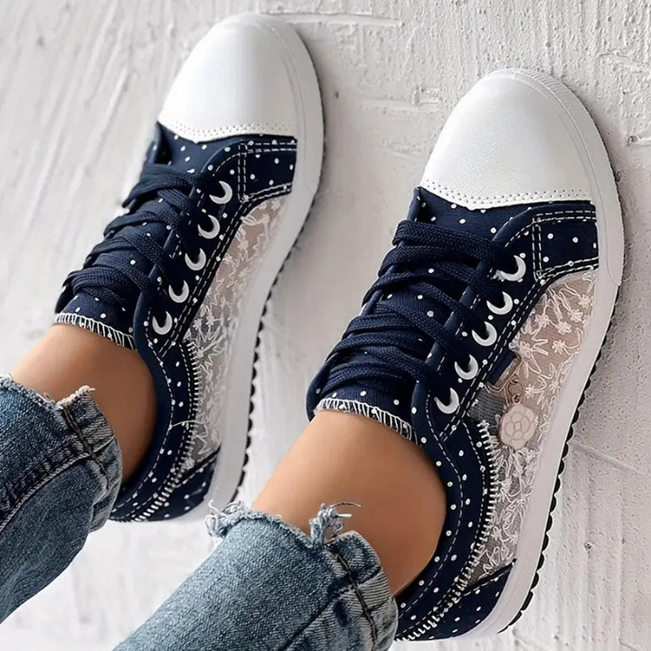 Navy sneakers with lace overlay, polka dots, and white contrast toe