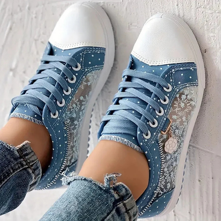 Pair of blue polka dot sneakers with lace panel and flower charm
