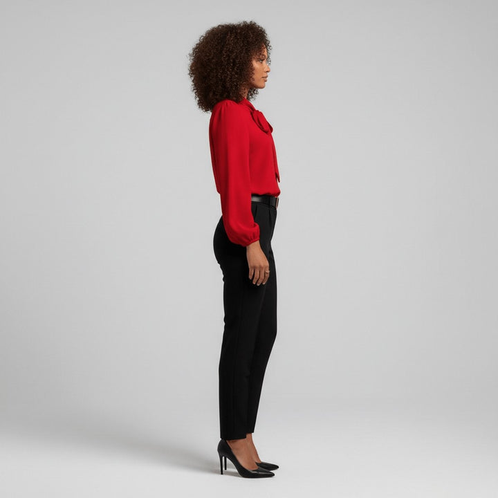 Side view of red bow-tie blouse tucked into black high-waisted trousers