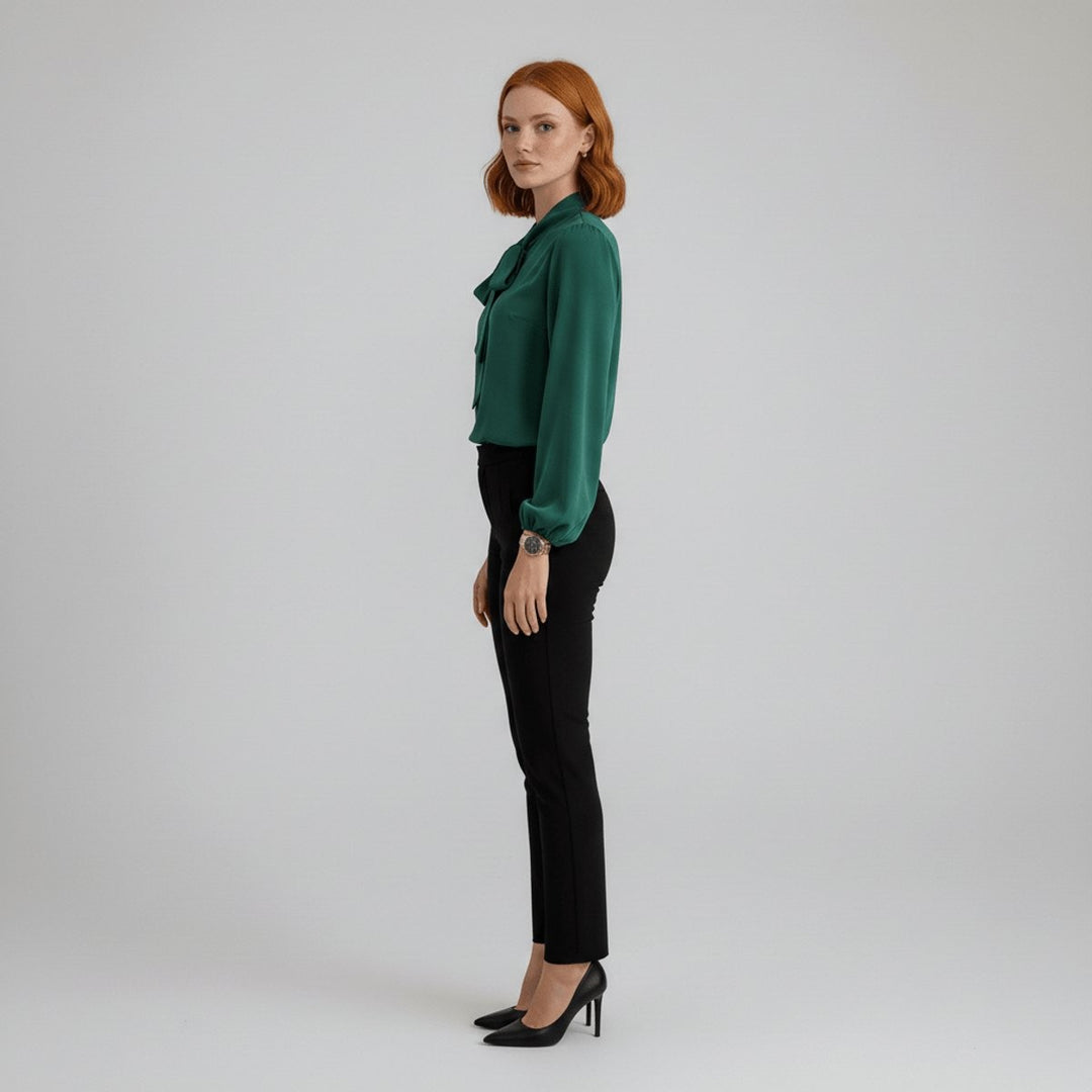 Side profile of green satin blouse with tie collar and black slim pants