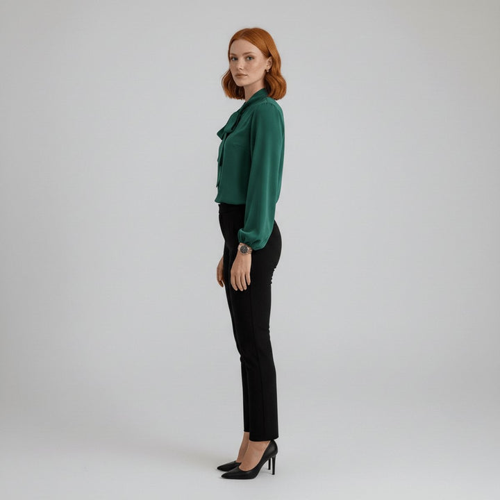 Side profile of green satin blouse with tie collar and black slim pants