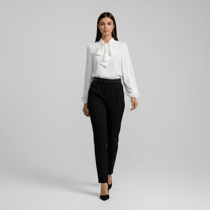 White relaxed-fit blouse with tie collar styled with black tapered pants and heels