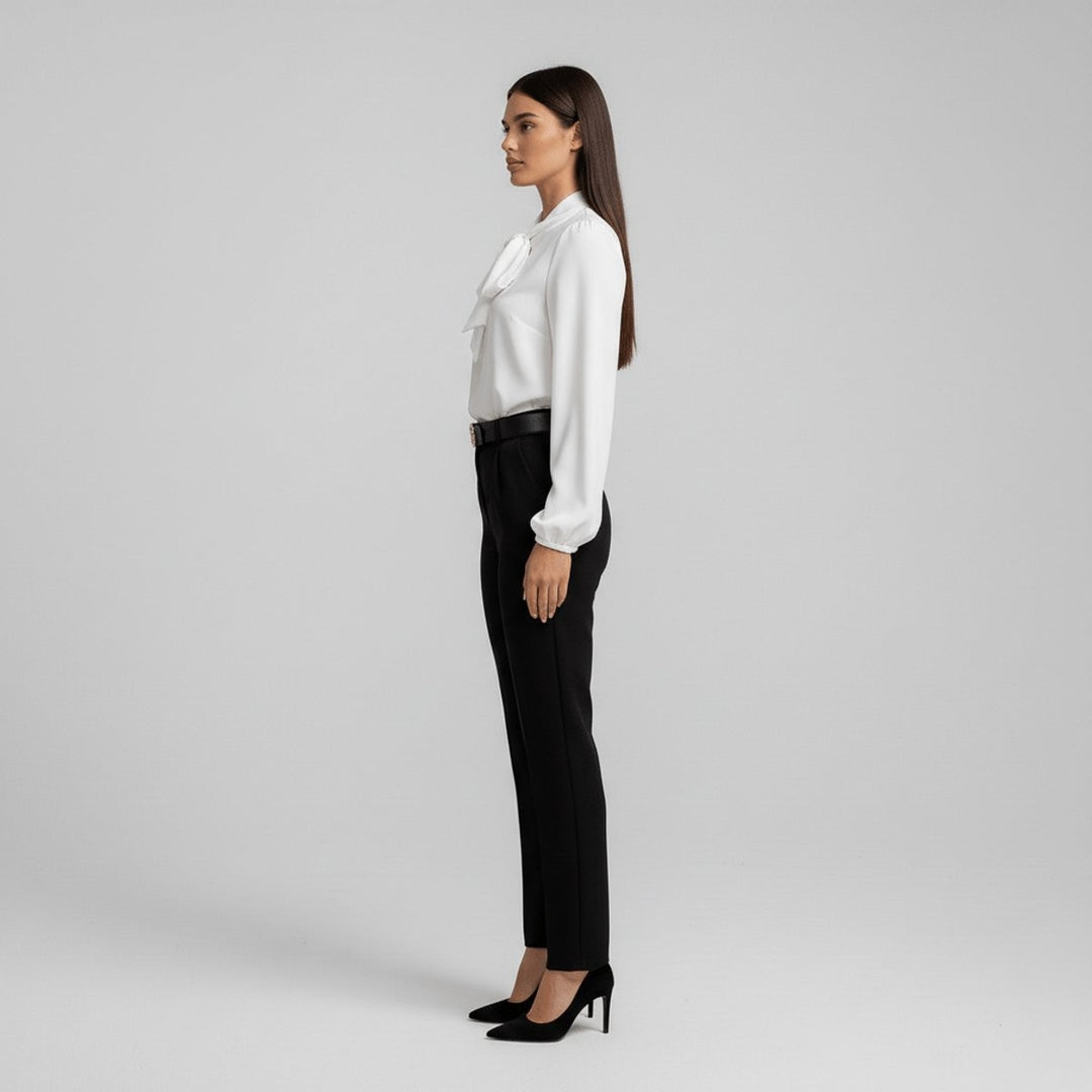 Side view of white tie-neck blouse tucked into black trousers with belt
