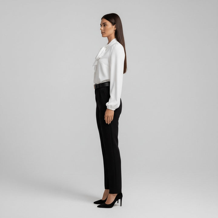 Side view of white tie-neck blouse tucked into black trousers with belt