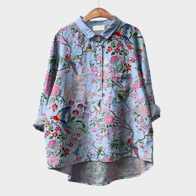 Light blue high-low blouse with colorful floral and parrot print, chest pocket detail