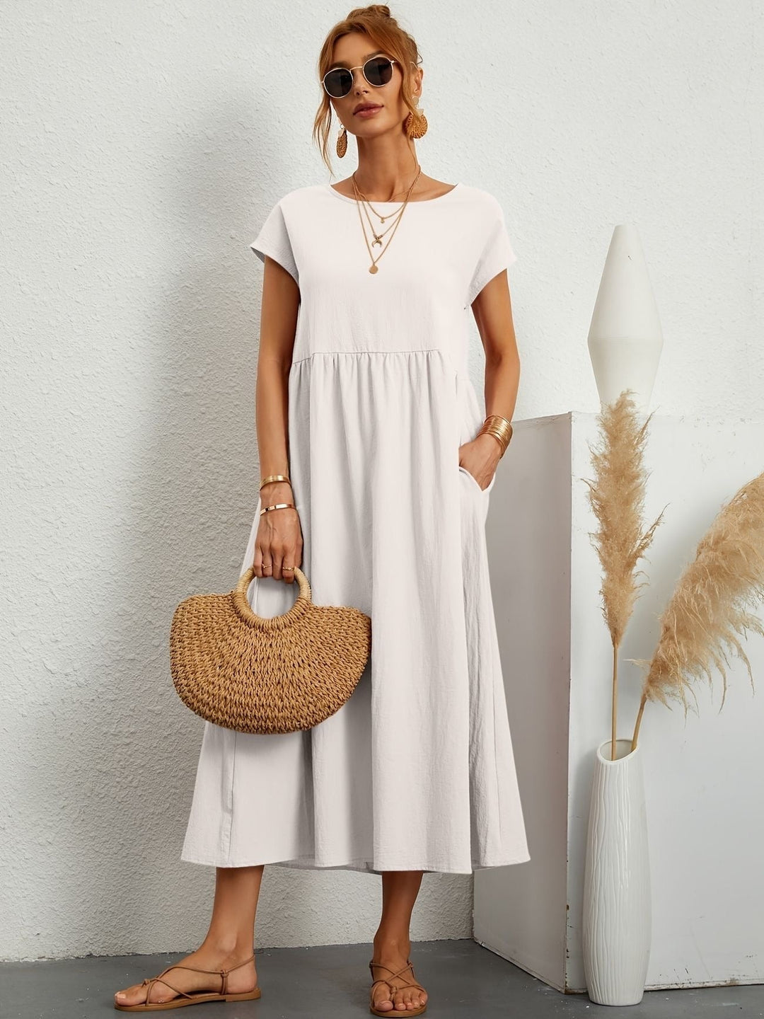off-white cap-sleeve maxi dress paired with woven straw handbag