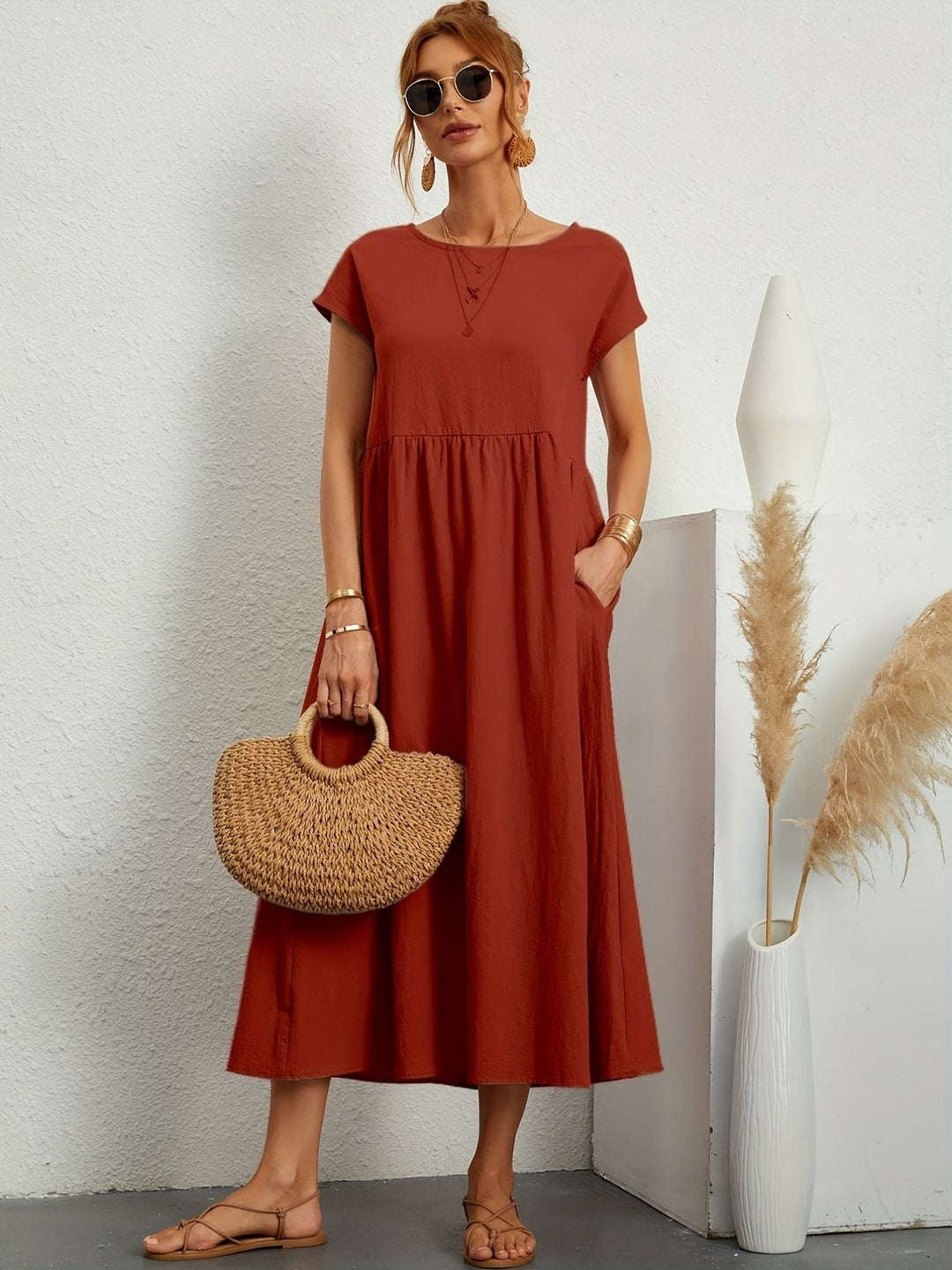 rust orange cap-sleeve maxi dress paired with woven straw tote