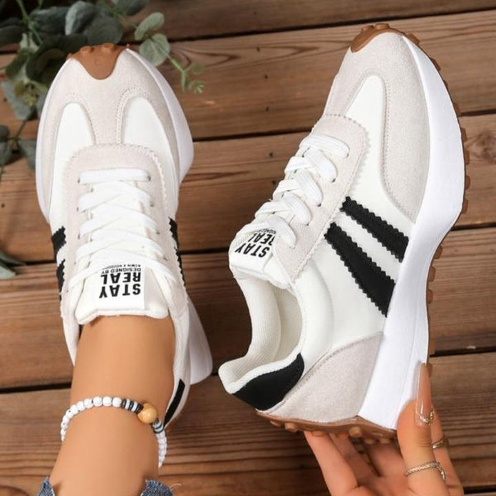 Off-white chunky sneakers with black stripes and gum sole held by hand
