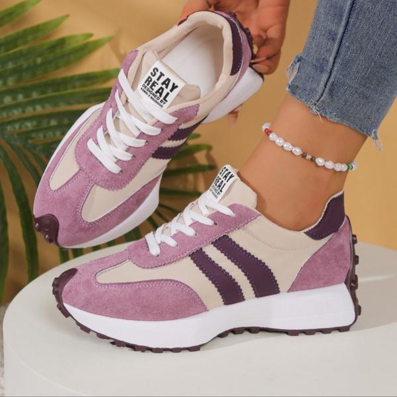 Mauve and cream platform sneakers with dark purple stripe detailing worn on ankle