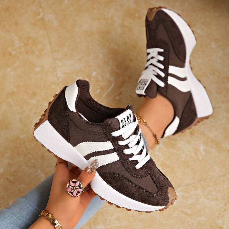 Brown suede chunky sneakers with white stripes worn on model's feet
