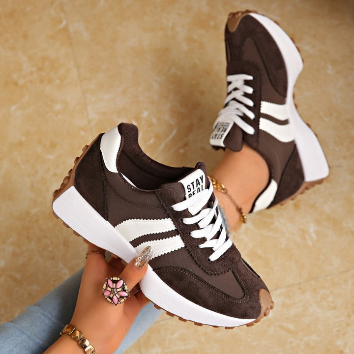 Brown suede chunky sneakers with white stripes worn on model's feet