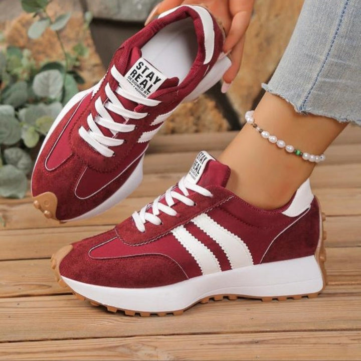 Burgundy lace-up platform sneakers with white stripe accents on model