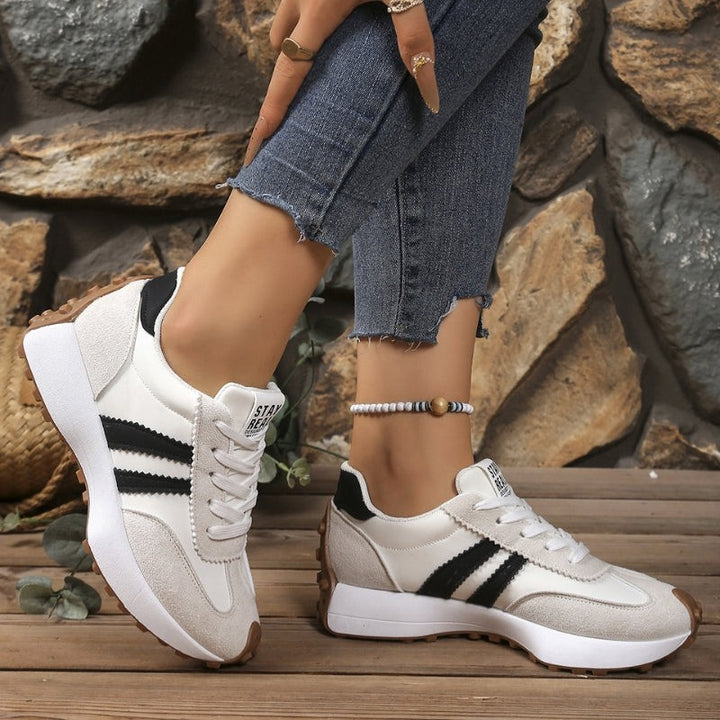 White and black retro sneakers with chunky sole worn with cropped jeans