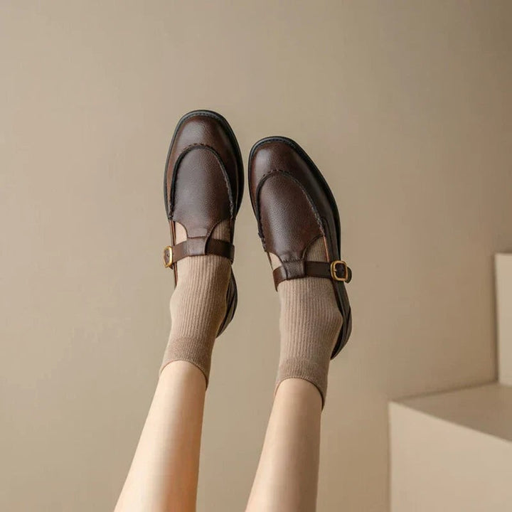 Dark brown leather Mary Jane shoes with gold buckle straps worn with taupe socks