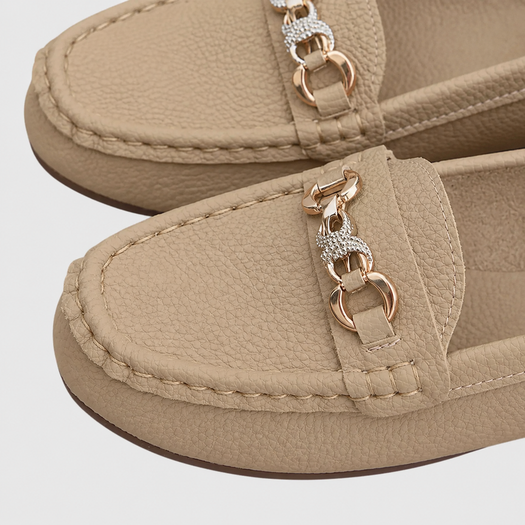 close-up of beige loafers highlighting gold chain and rhinestone trim