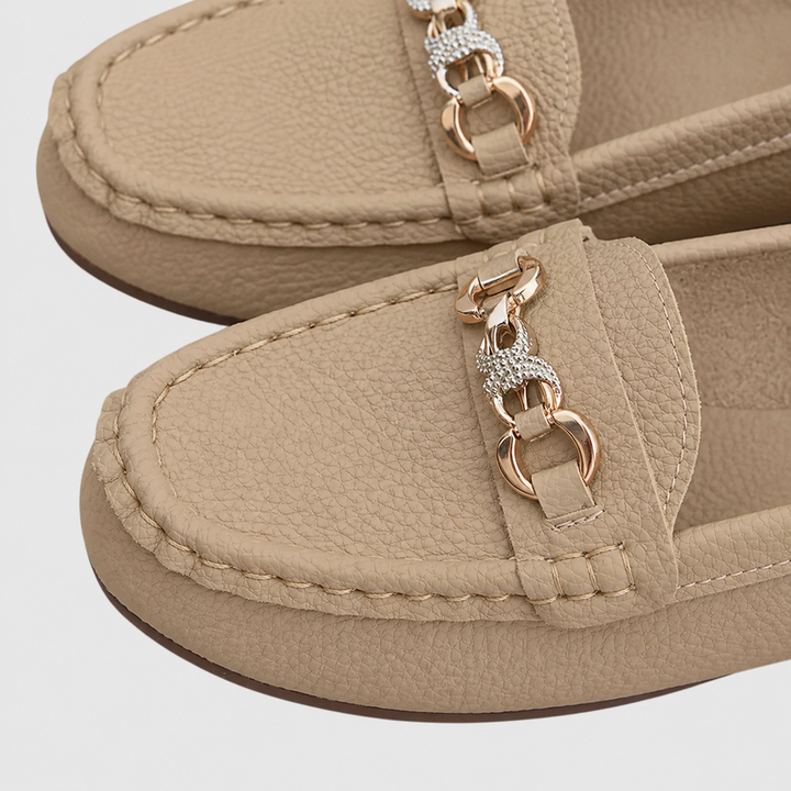 close-up of beige loafers highlighting gold chain and rhinestone trim