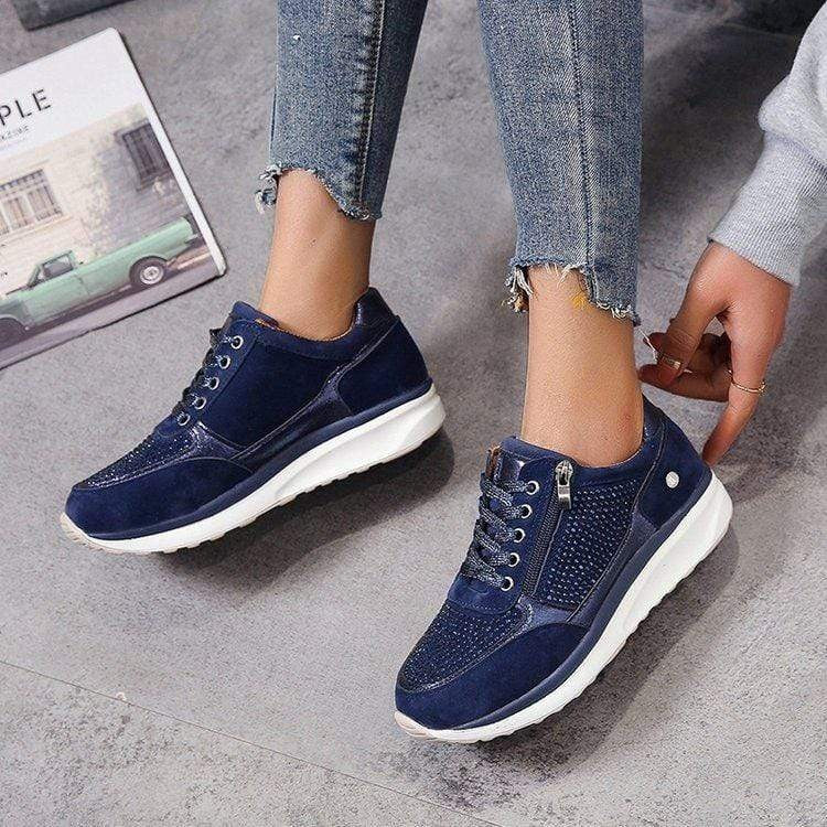 Navy blue platform sneakers with rhinestone detailing and side zipper, worn with jeans