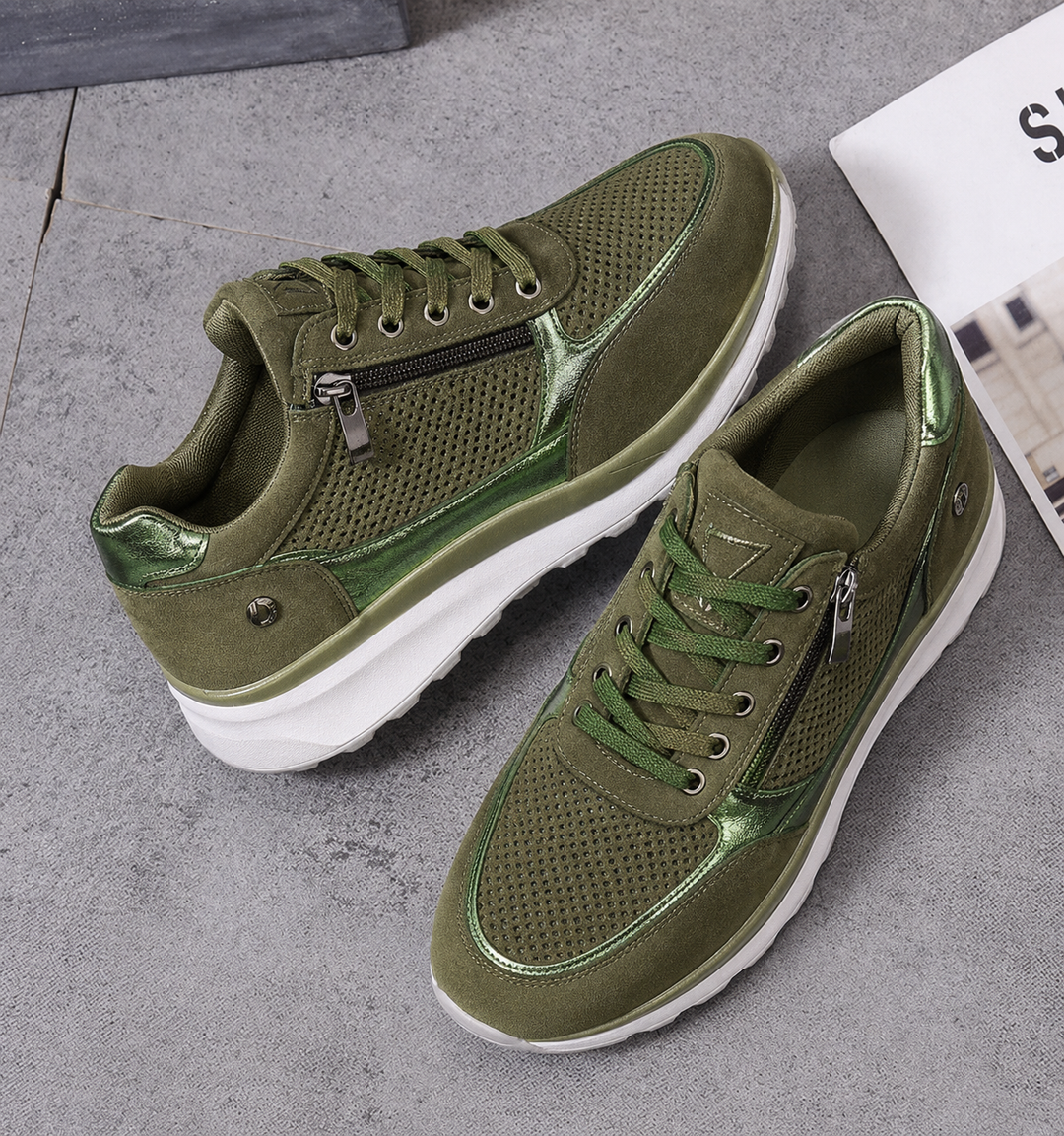 Pair of olive green platform sneakers with zipper and metallic trim resting on floor