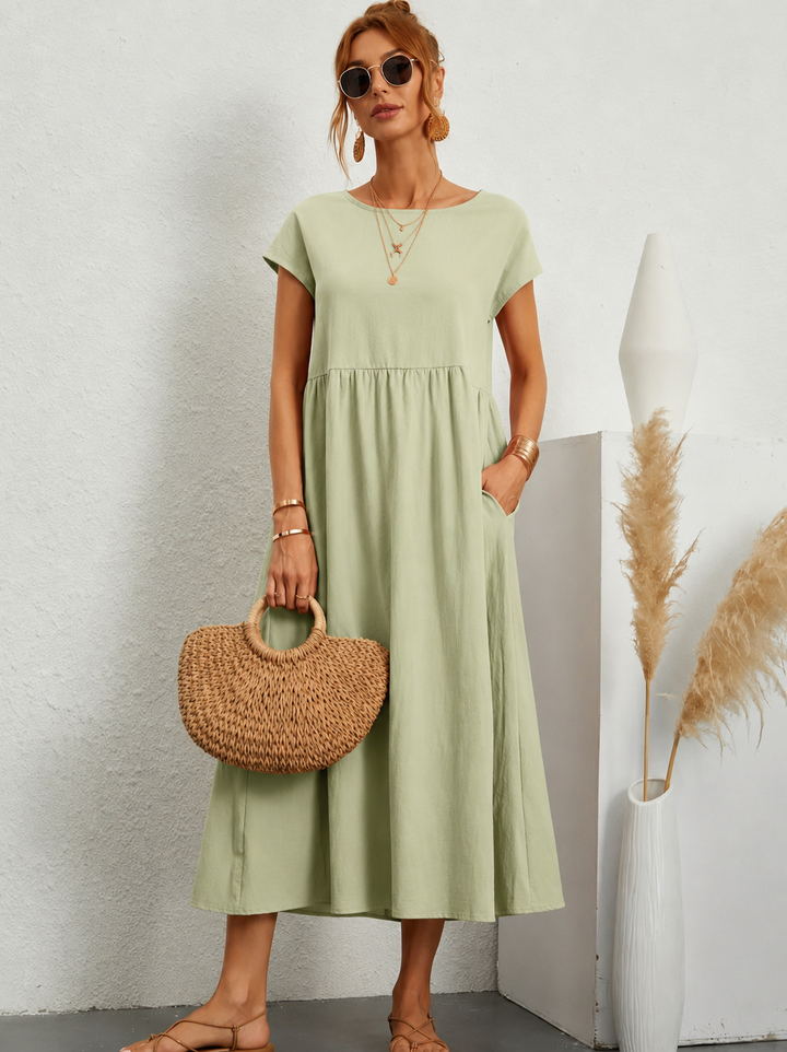 Sage green maxi dress with cap sleeves paired with woven straw bag