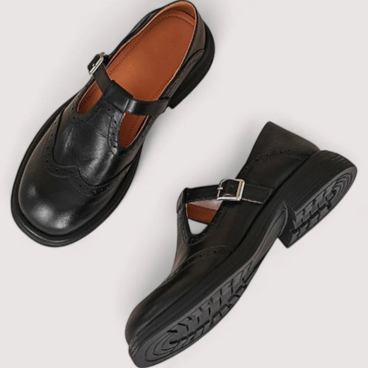 Black leather Mary Jane shoes with wingtip perforated detailing and silver buckle straps