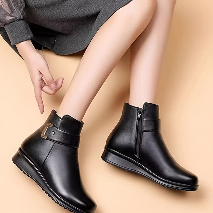 woman seated wearing black buckle ankle boots with side zip closure