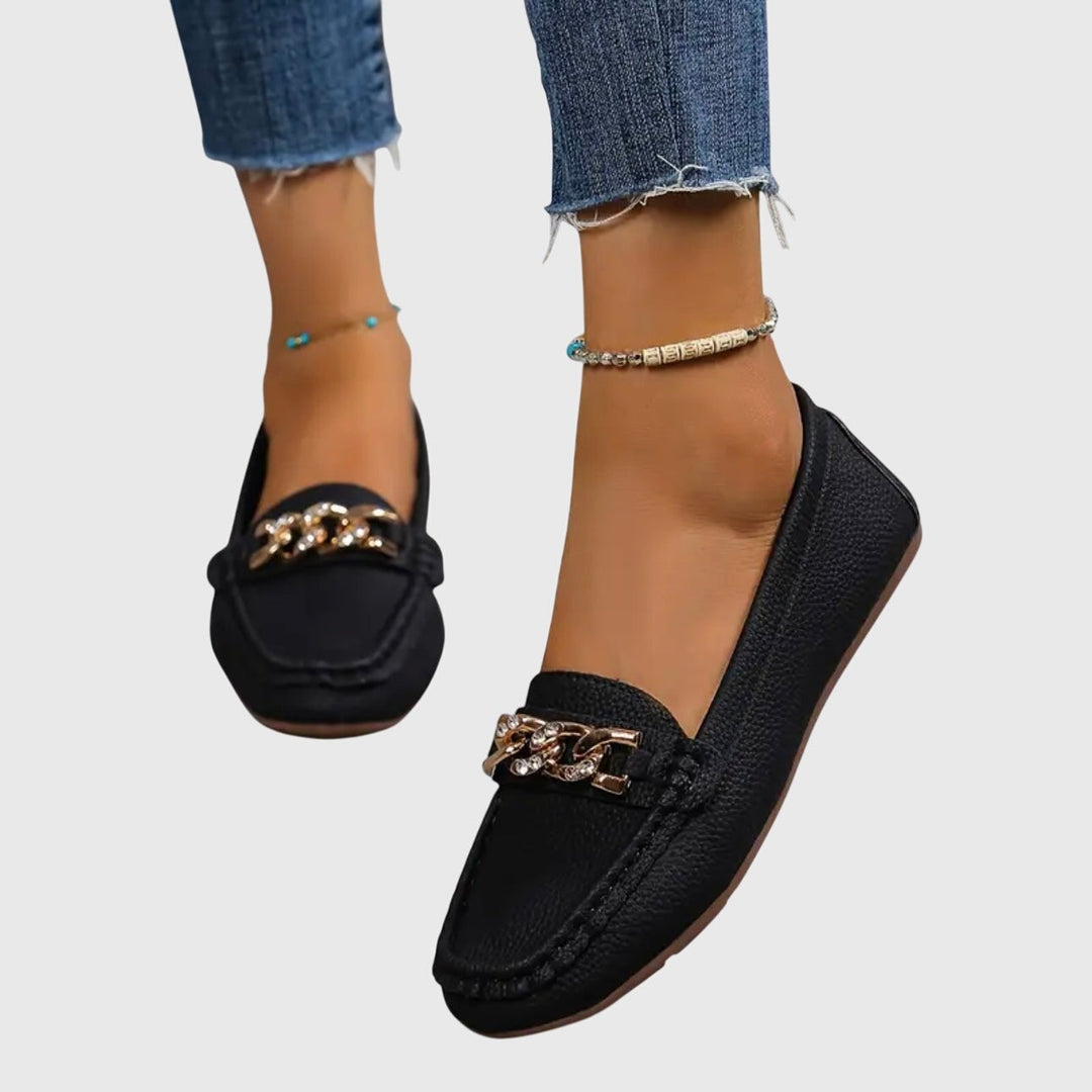 pair of black slip-on loafer flats featuring gold chain and rhinestone trim