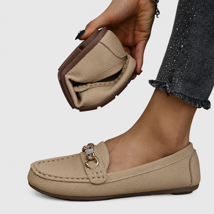 beige textured loafer flat held by hand showing flexible rubber sole