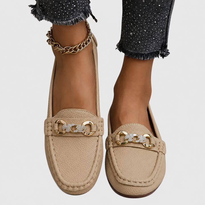 beige leather slip-on loafers with crystal chain detail worn on feet