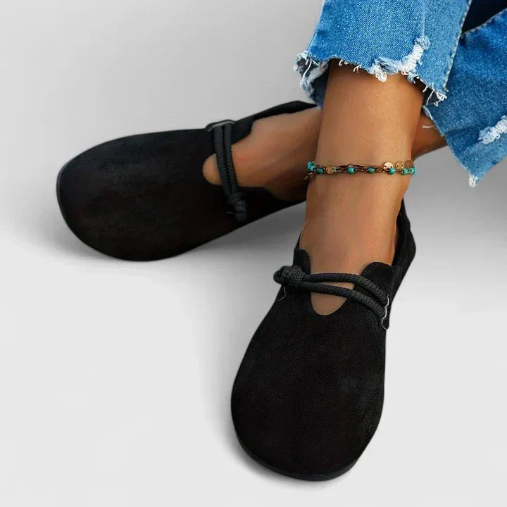 black suede flats worn on feet showing cutout Mary Jane strap