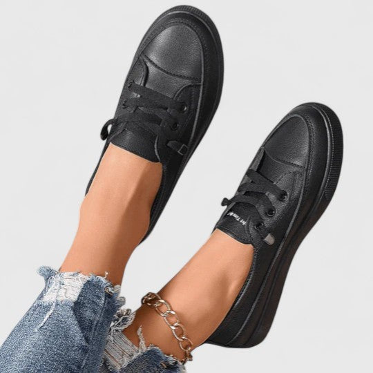 Black leather platform sneakers with laces, top-down view on model's feet