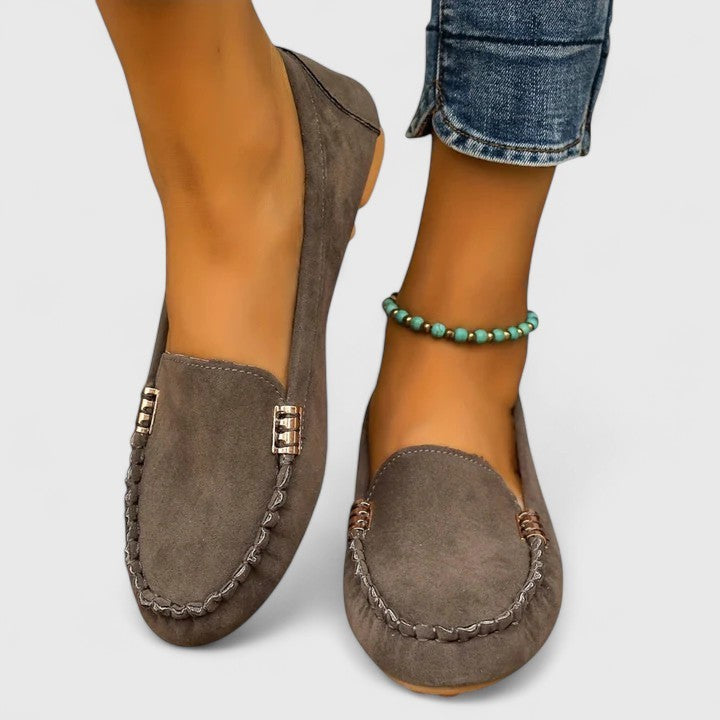 Taupe suede slip-on loafer featuring moc-toe stitching and gold accent