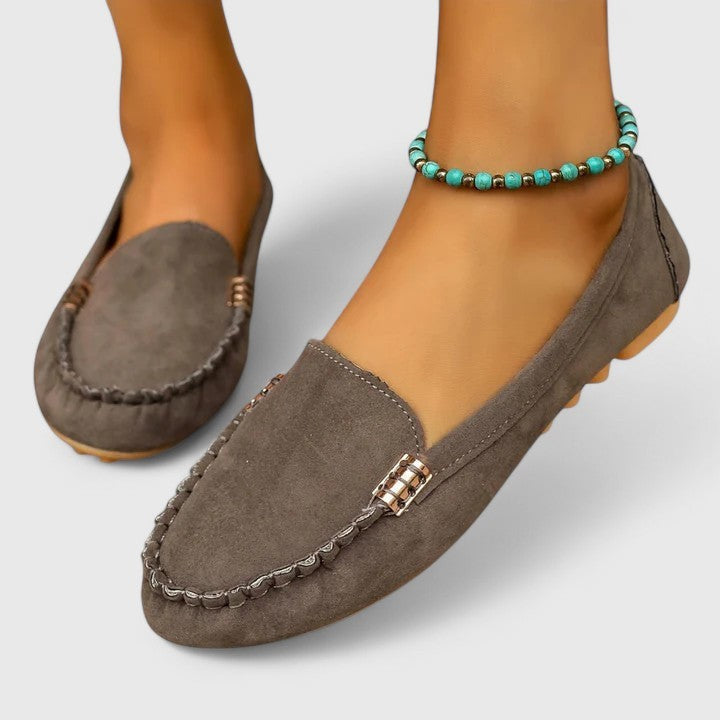Gray suede moccasin loafer showing stitched toe and gold buckle detail