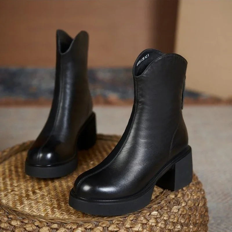 Black leather Chelsea boots displayed on woven jute stool