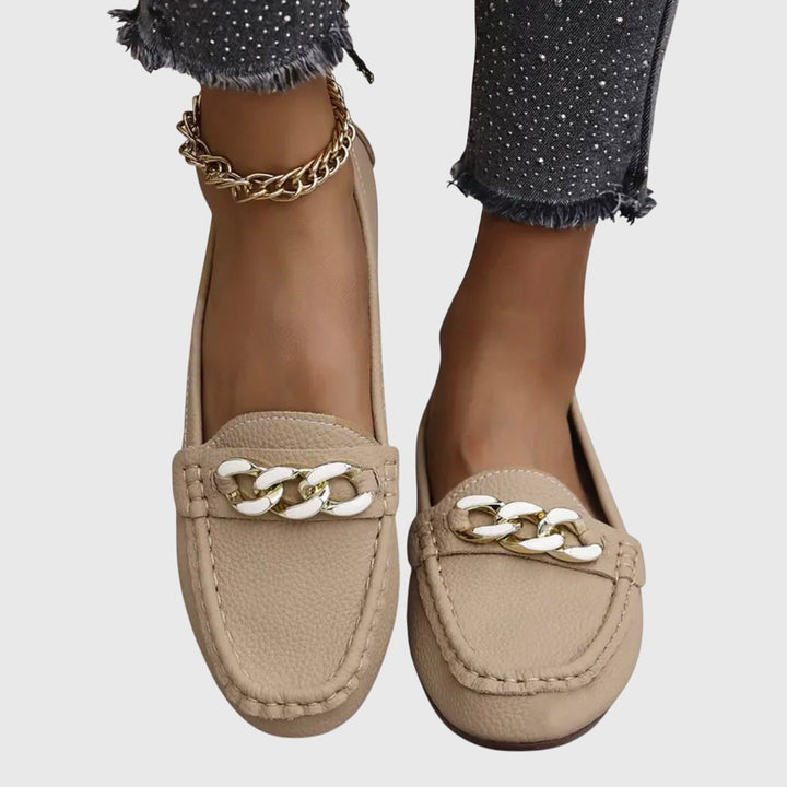 Beige leather loafers with white and gold chain detail, worn on feet