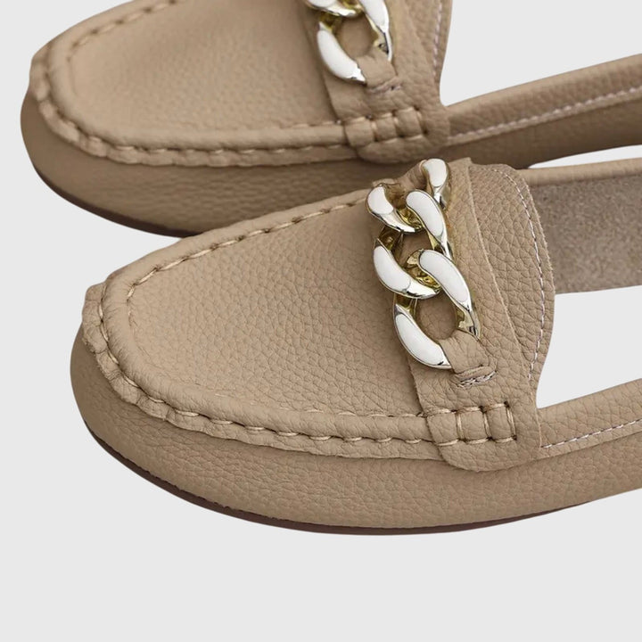 Close-up of tan loafer toe showing gold chain hardware and stitching