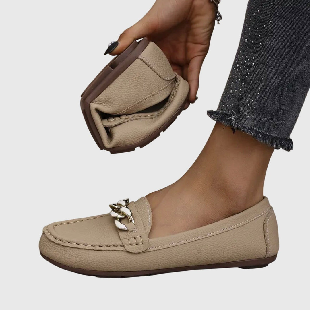 Beige leather loafer held in hand showing padded footbed and sole