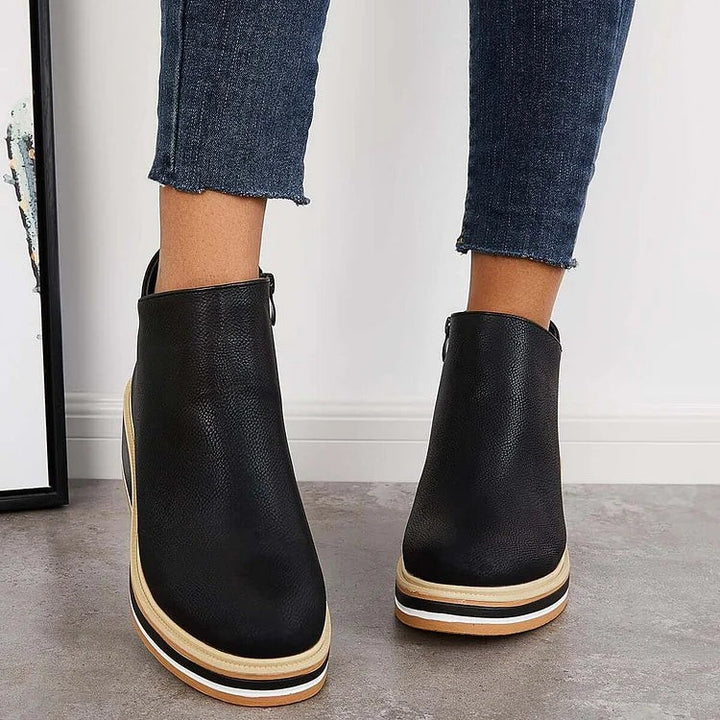 Black ankle boots in motion showing tan and white wedge heel detail