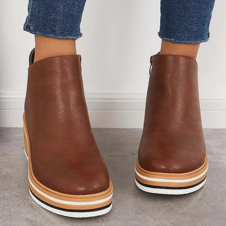 Back view of brown leather ankle boots showing tan striped wedge sole