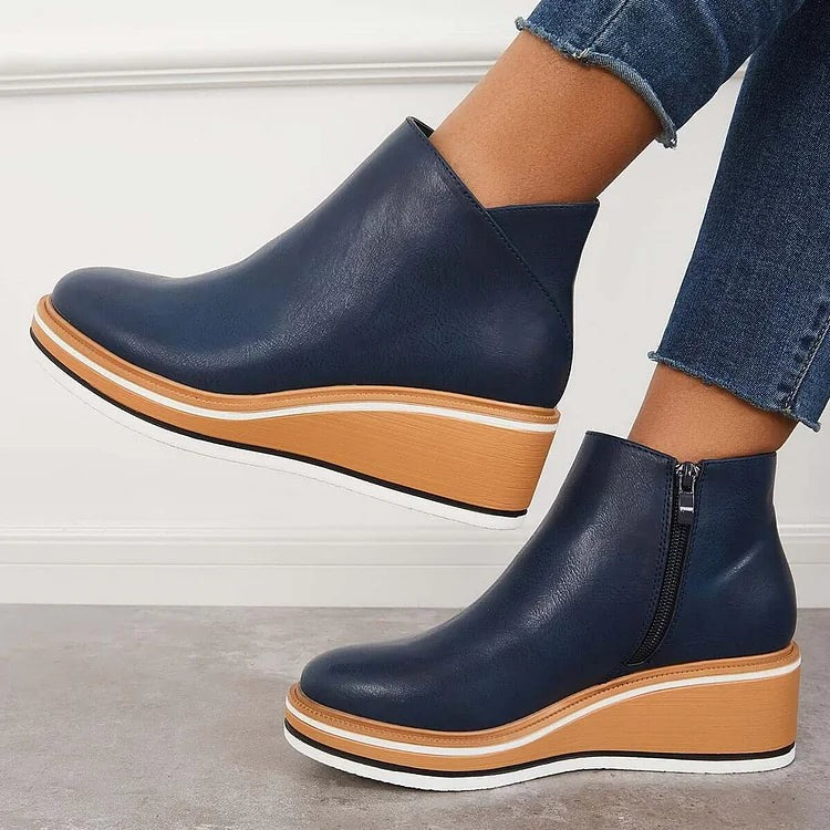 Side profile of navy ankle boots with tan and white striped wedge sole