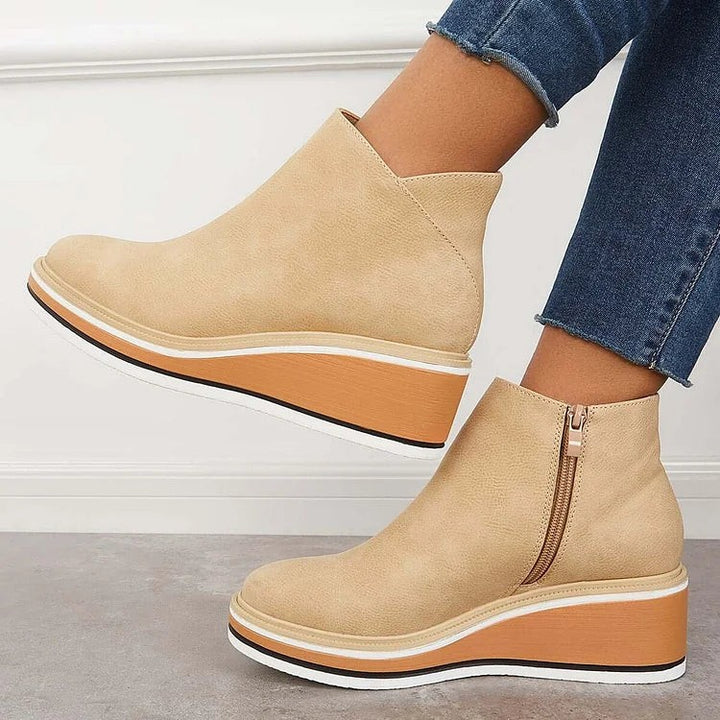 Tan ankle booties in motion showing tapered wedge heel design