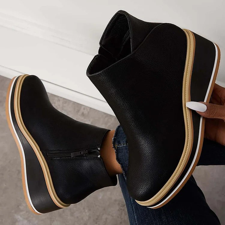 Black leather ankle boots with tan zipper pull and platform wedge sole