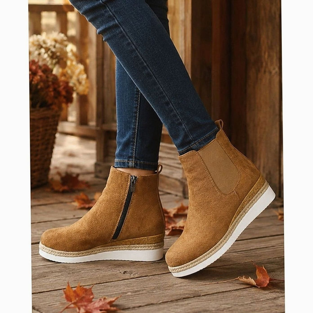 Tan suede wedge Chelsea boots worn with skinny jeans on a wooden porch