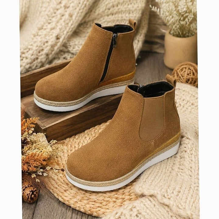 Pair of tan suede Chelsea wedge boots displayed on a woven mat