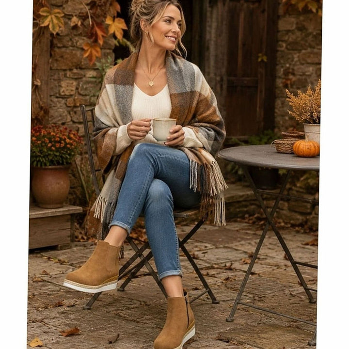 Woman wearing tan suede wedge boots with jeans and check wrap outdoors