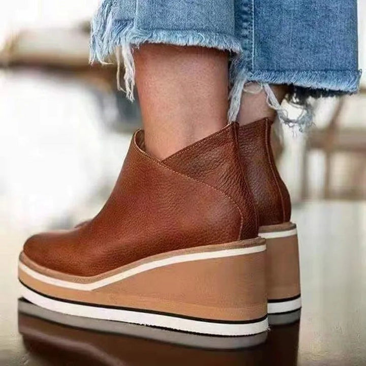 cognac leather wedge booties showing back seam and striped sole detail