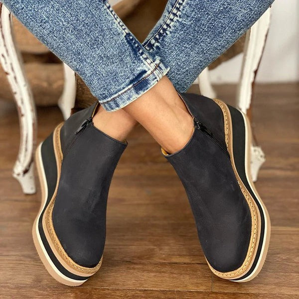 black leather zip-up wedge boots with tan and cream striped sole
