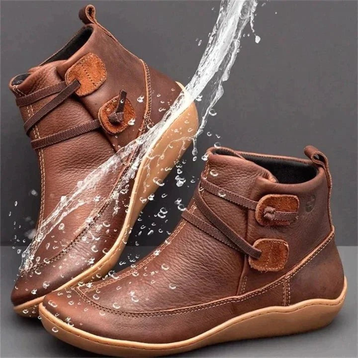 Brown leather ankle boots with buckle strap, shown splashed with water for waterproof appeal