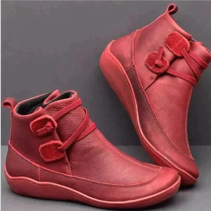 Red leather ankle boots featuring double buckle straps and stitched sole detailing
